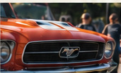 Voorkant van een oranjerode Mustang
